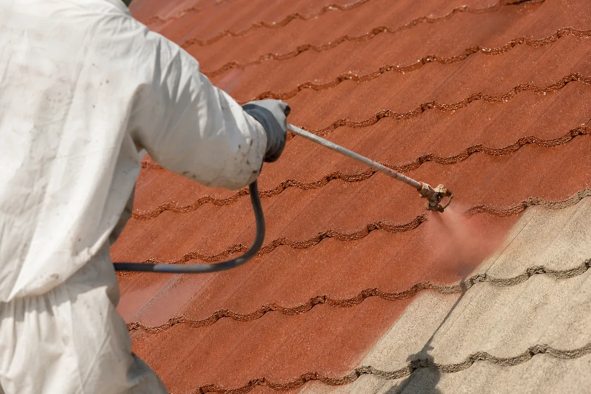 Application d’une résine colorée au pulvérisateur sur une toiture en tuiles béton
